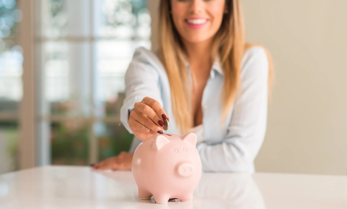 Woman putting coins into a piggybank